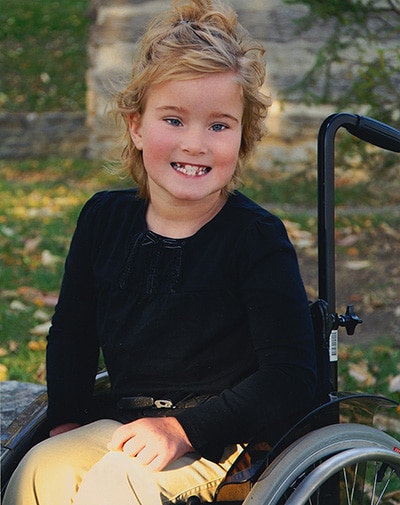 Elley smiling, sitting in a wheelchair.