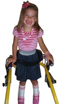 Una niña caminando con un andador.