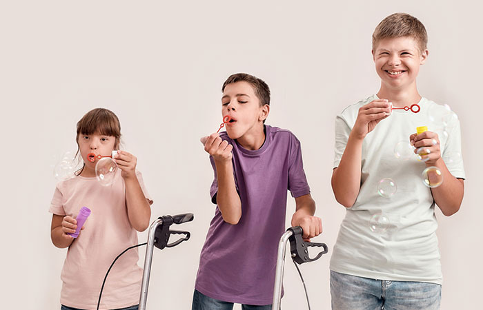 Happy children with disabilities blowing bubbles