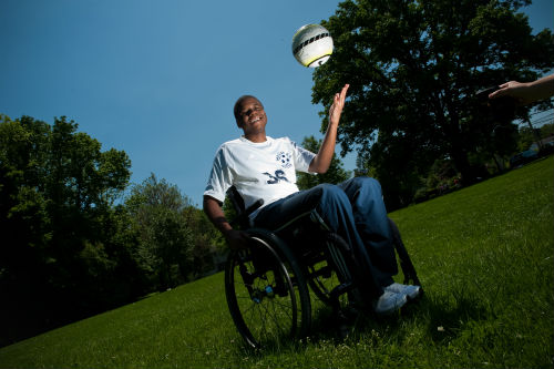 Photo of boy in wheelchair tossing a ball in the air