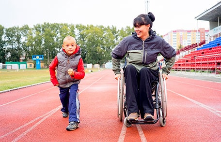Mujer en silla de ruedas con un niño preparándose para correr