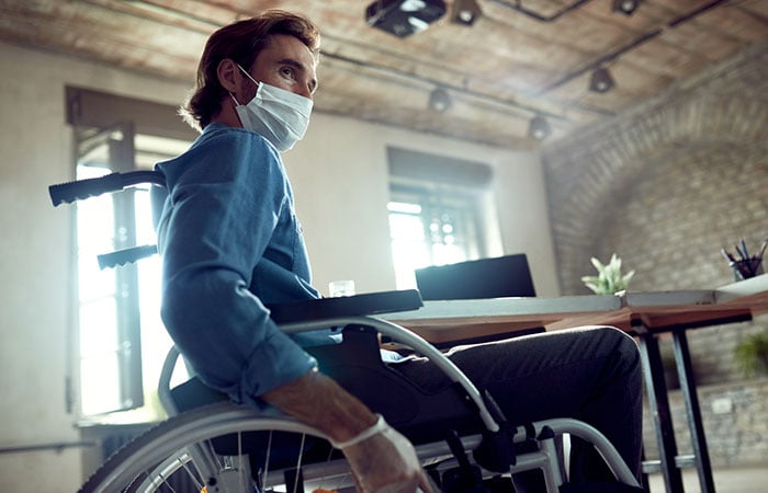 Man in a wheelchair wearing a protective face mask