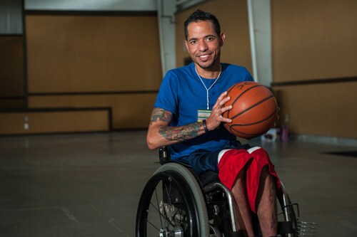 Man in a wheelchair in a gym holding a basketball