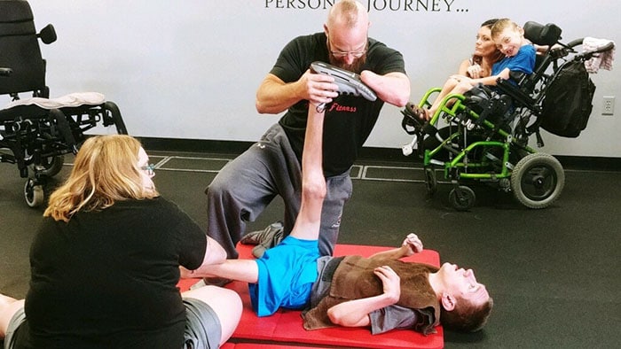 Trainer stretching boys legs in gym