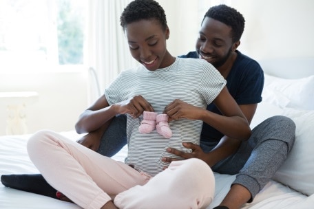 Pregnant women holding baby clothes with her husband