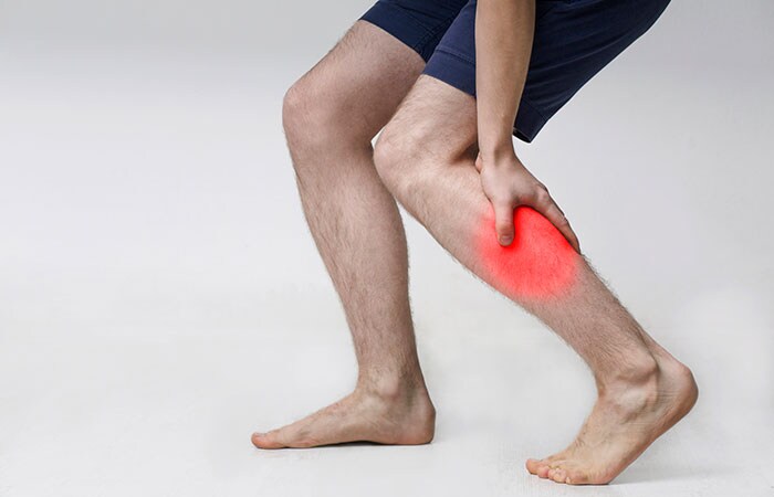 Man with injured calf, massaging painful leg muscle with red sore spot
