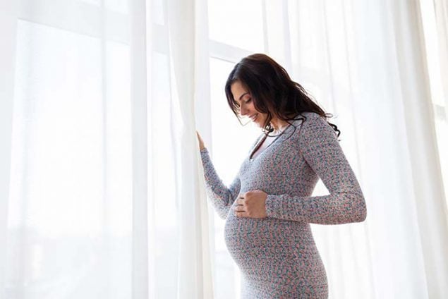 pregnant woman holding her stomach and smiling