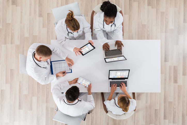 Healthcare providers with computers discussing electronic clinical data