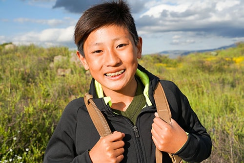 Young sporty Asian boy hiking the mountain