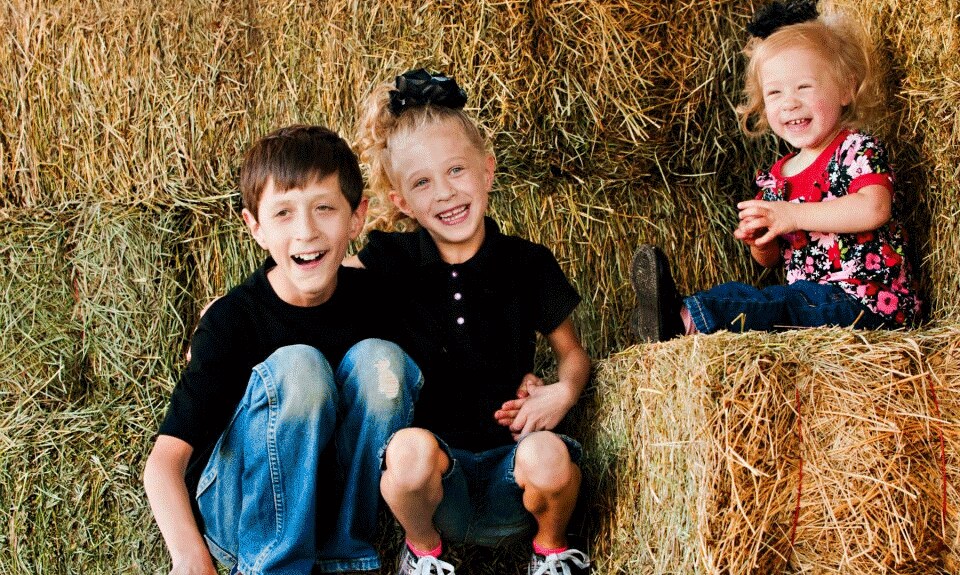 Kids sitting on a haystack