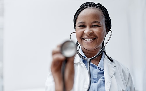 Black doctor in a white lab coat holding a stethoscope.