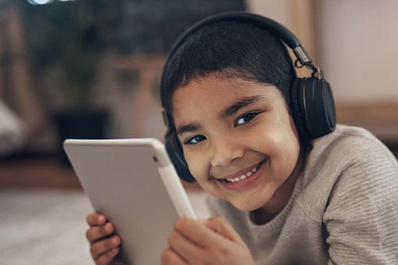 Boy wearing headphones holding tablet