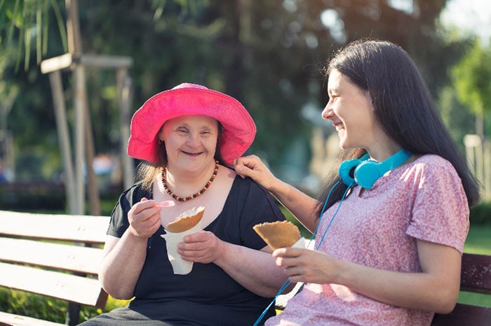 Woman with disability eating ice cream with her friend in the park