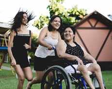 A group of three women, one of whom is in a wheelchair.