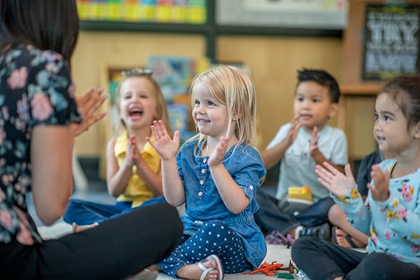 Preschool teacher and children sing together as a classroom activity