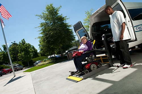 Woman in a wheelchair using a chair lift from a vehicle