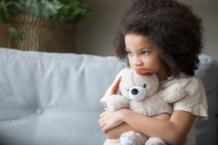 Upset lonely african kid girl holding teddy bear looking awa…