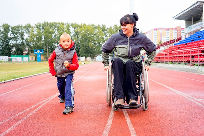 A woman in a wheelchair and a boy exercising on a running track