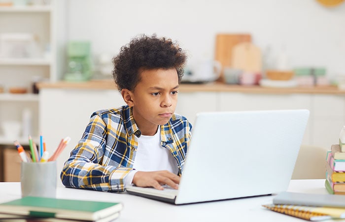 Portrait of teenage African American boy using laptop while studying at home