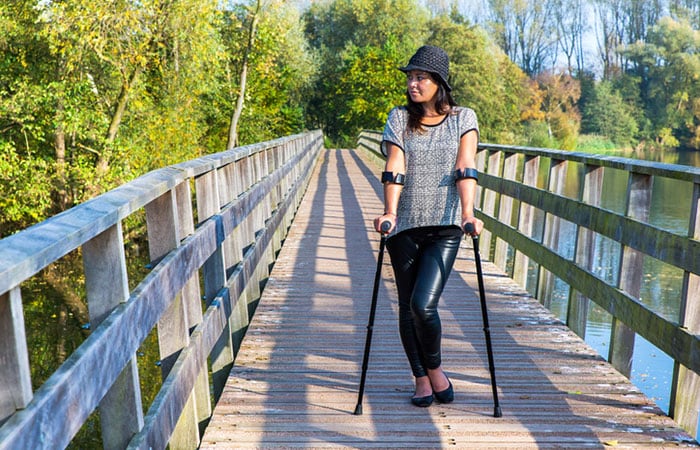 A young woman walking with crutches in the park
