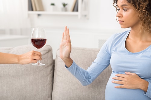African-american pregnant woman rejecting alcohol at home