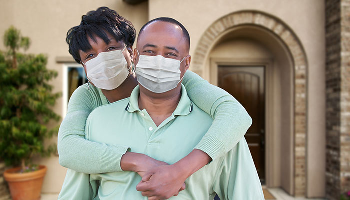 Loving African American Couple Hugging Wearing Medical Face Masks In Front of House