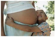 Un ni%26ntilde;o peque%26ntilde;o abrazando el vientre de su mam%26aacute; embarazada