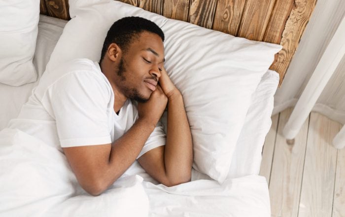 African American Man Sleeping Peacefully In Comfortable Bed…