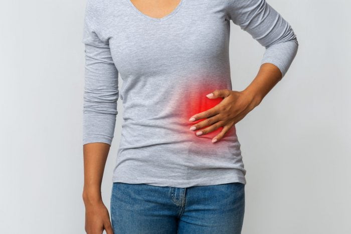 Woman in pain holding her stomach on the left side