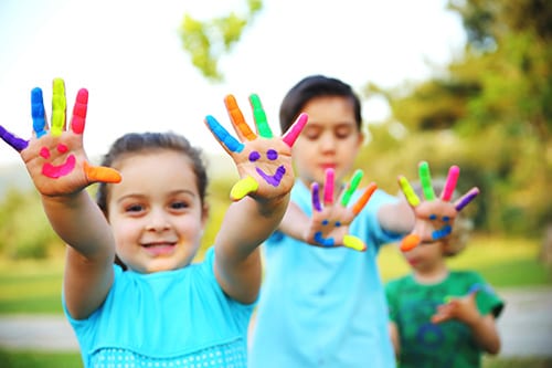 Los niños con caras sonrientes pintadas en sus manos