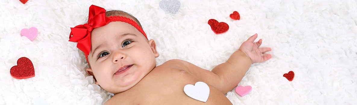 Infant laying on rug with hearts all around