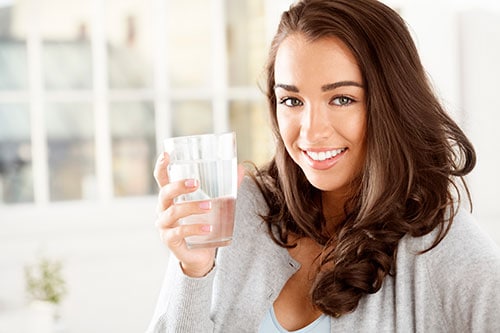 Una mujer joven que bebe un vaso de agua