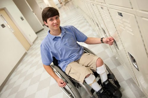 A teen boy with spina bifida at his school locker