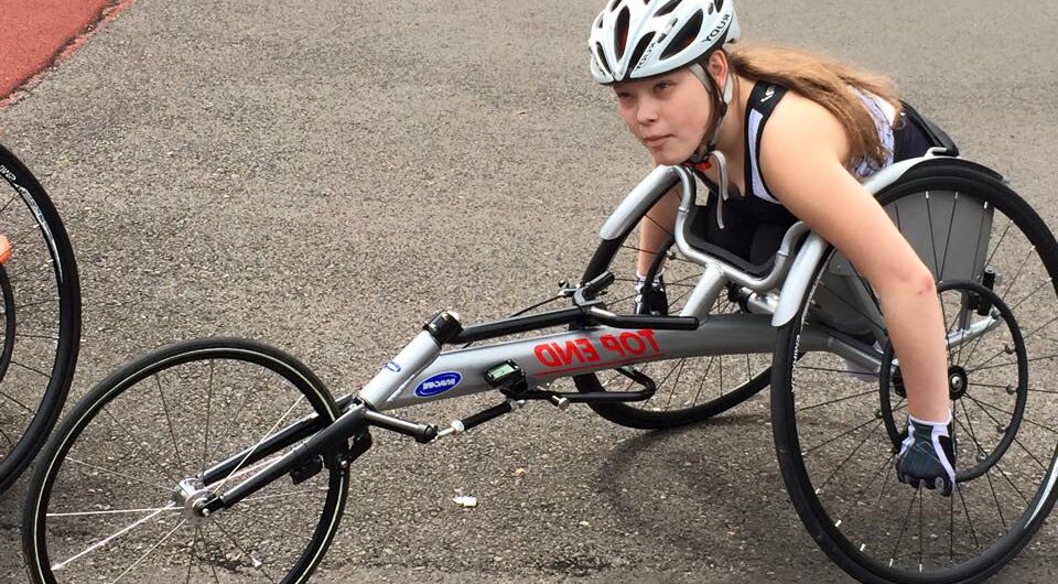 Young woman in wheelchair racing bike.