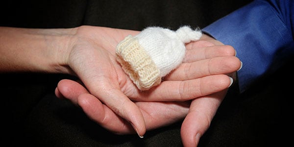 Hands holding a baby mitten