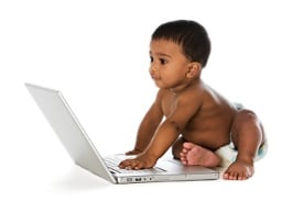 A toddler playing with a laptop computer