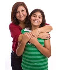 Mother standing behind daughter and hugging her.