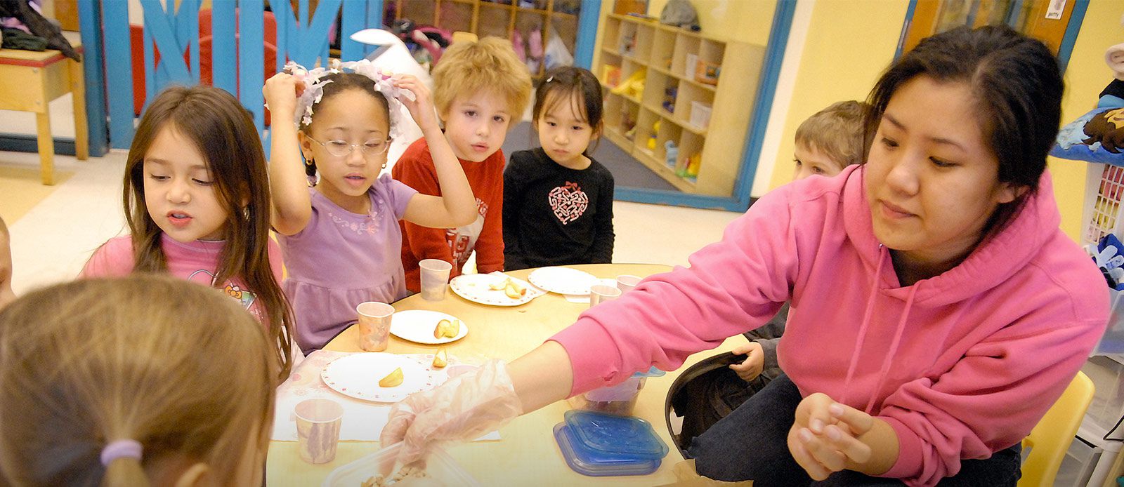 A childcare provider serves snacks to the children at her center.