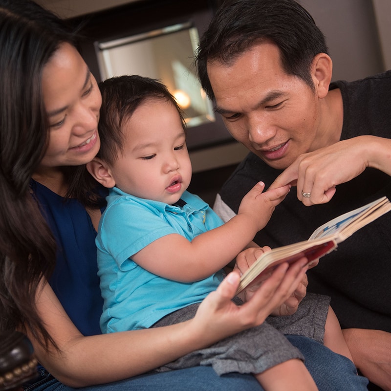 Toddler looking at a book with her parents