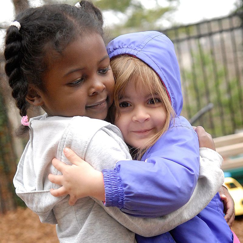 Dos niñas se abrazan en el patio de juegos.