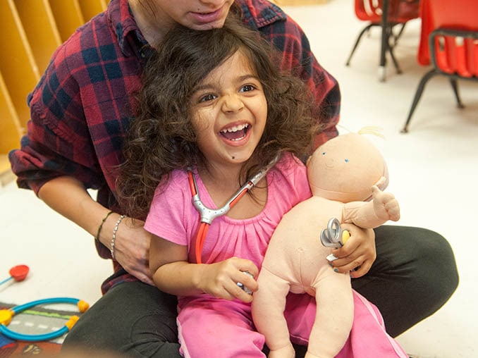 Una niña juega al doctor con un muñeco.