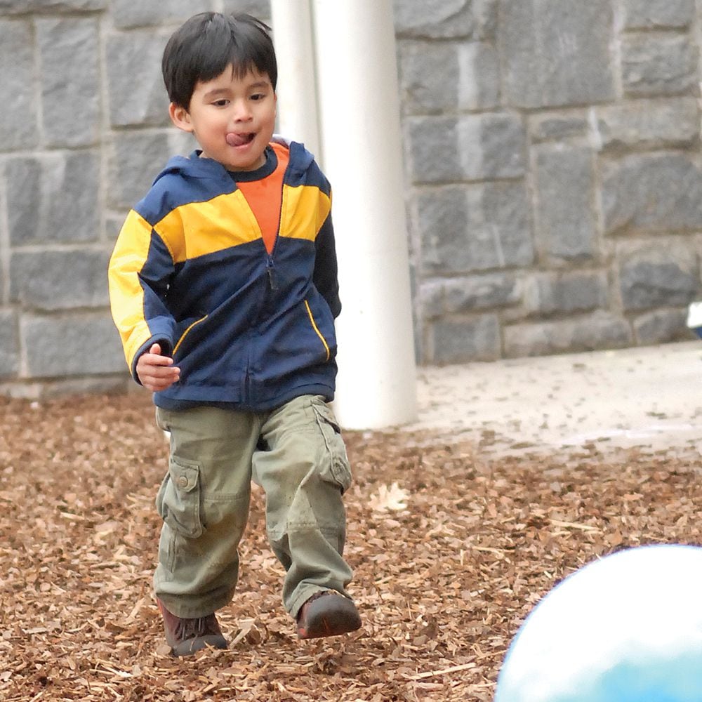 Un niño corre por el patio de juegos de una guardería.