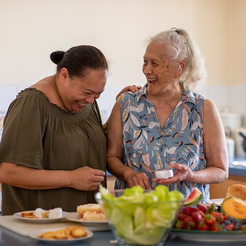 Senior Pacific Islander woman and her mature daughter preparing food together in their kitchen at home.