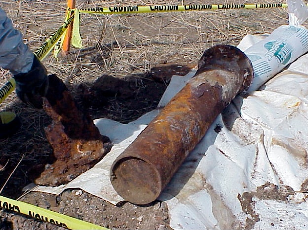 Rusted chemical agent filled mortar next to hole where it was excavated.