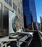 Photo of an outdoor HVAC air conditioner unit located on a high-floor porch of a New York skyscraper.