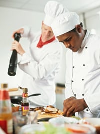 Photo of chefs preparing food in a kitchen.