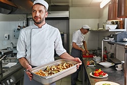Chef with carrying food in a shallow pan.