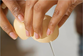 Woman's hands cracking a raw egg.