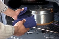 Photo of chef removing pot from oven.