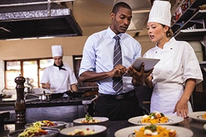 Photograph of a kitchen manager discussing guidelines with a chef.